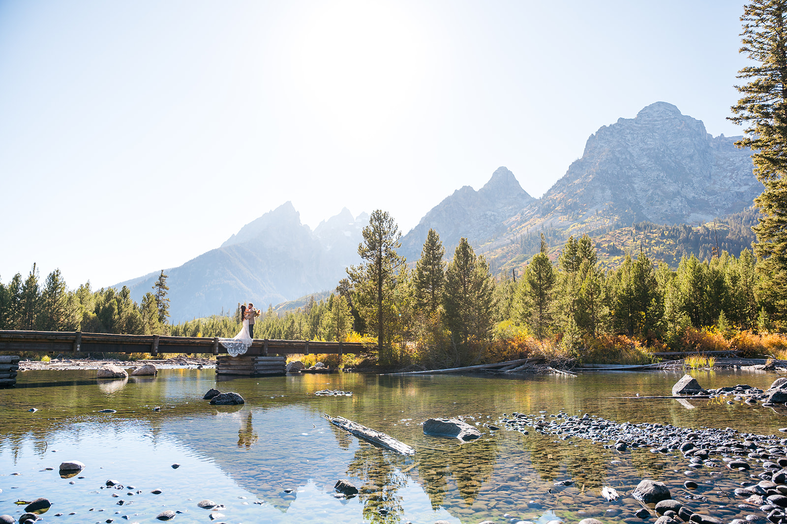 Bride and groom on a bridge in front of the Grand Tetons